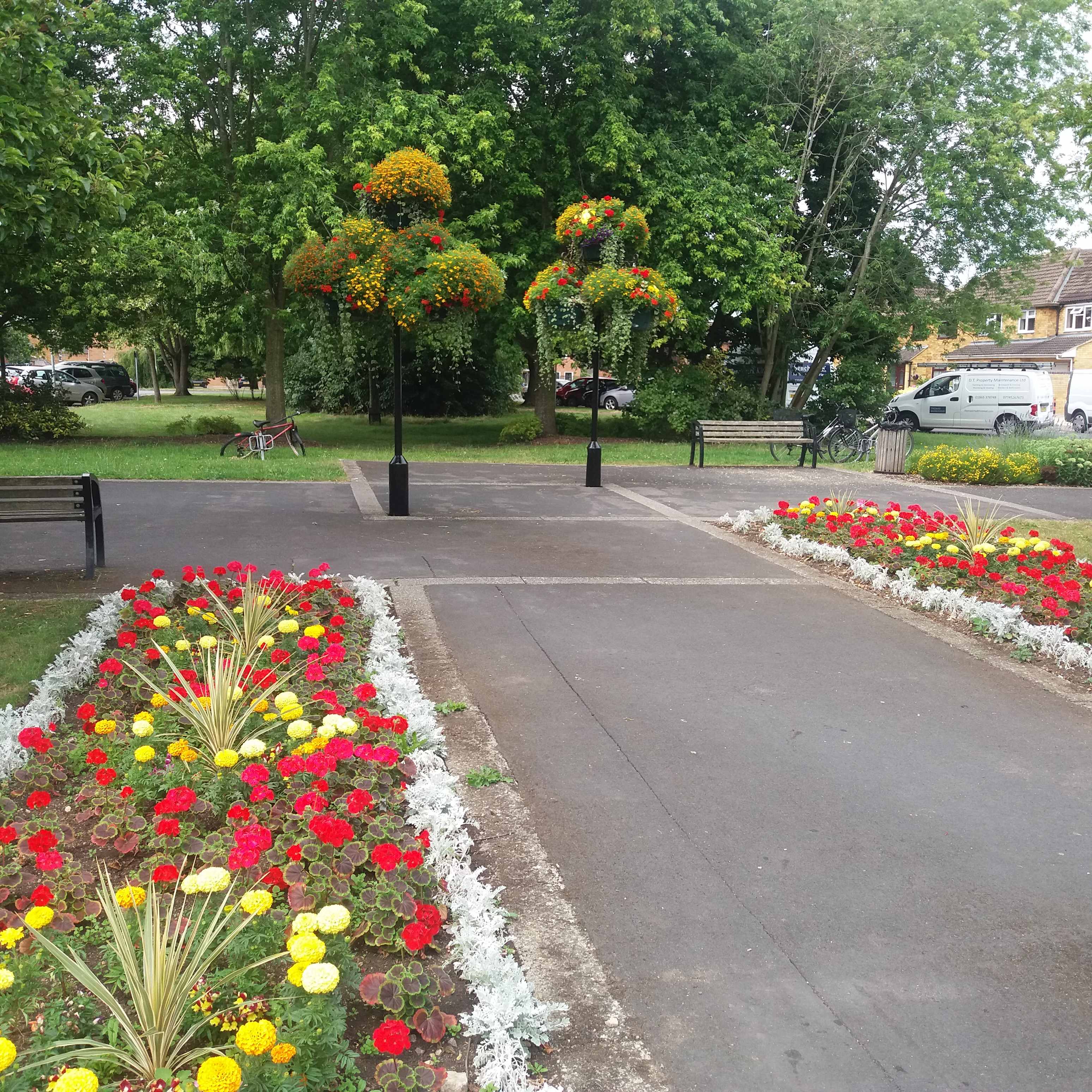 two trees at the end of a path with flowers either side